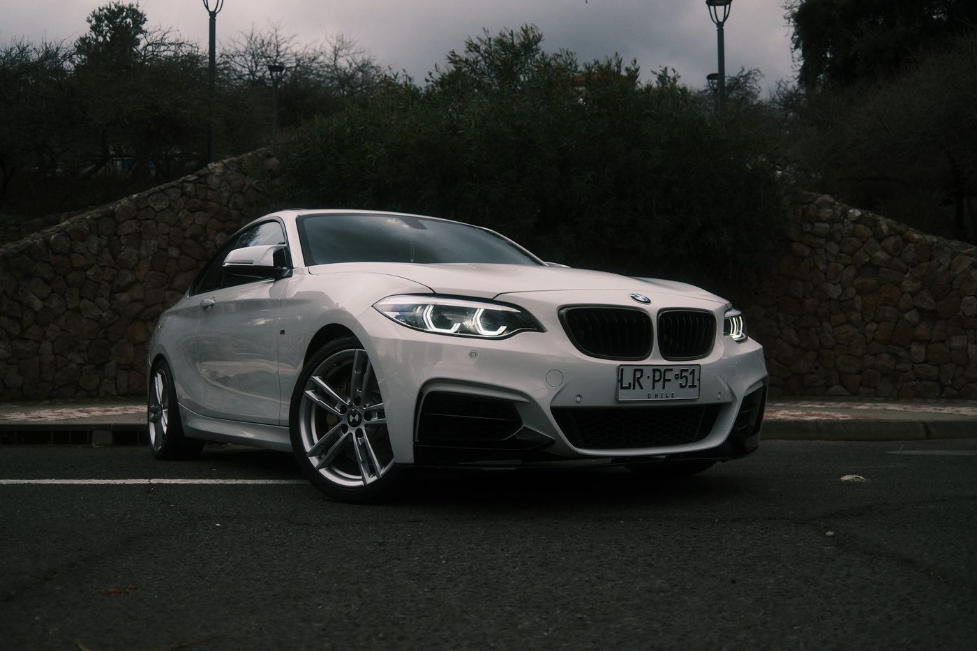 BMW M240i estacionado frente a un muro de piedra